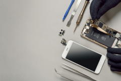 Technician repairing broken smartphone on desk